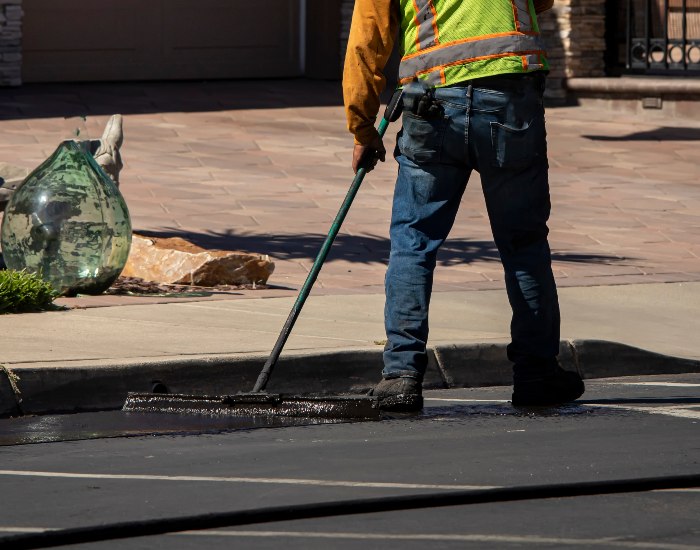 Worker from Driveways 2Day in Frederick, MD, applying asphalt seal coating on a driveway